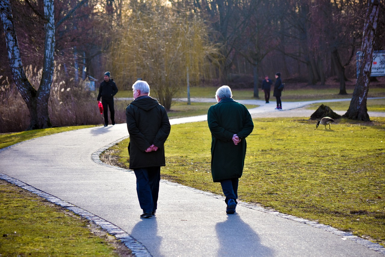Personas mayores caminando por un parque.