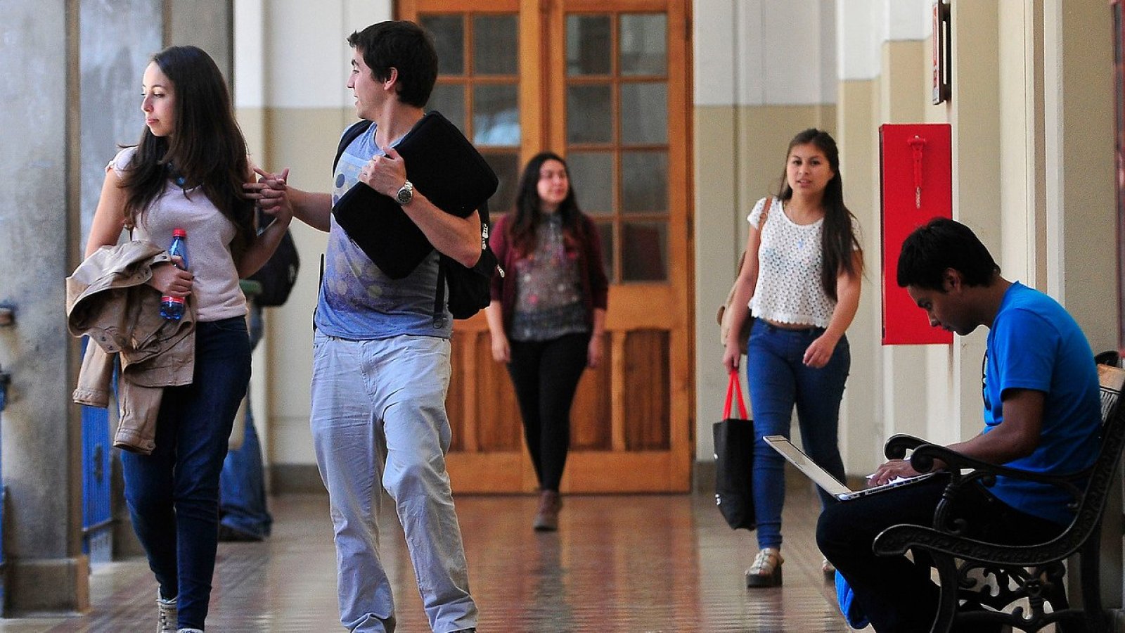 Estudiantes caminando por un pasillo universitario.