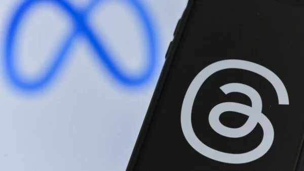 Logo de Meta en un computador y teléfono celular con el logo de Threads.
