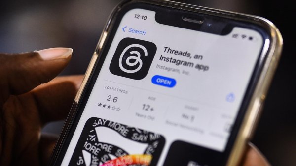 Mano sujetando un teléfono descargando la app de Threads.