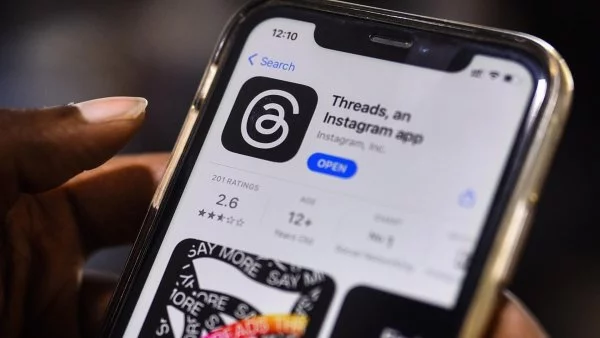 Mano sujetando un teléfono descargando la app de Threads.