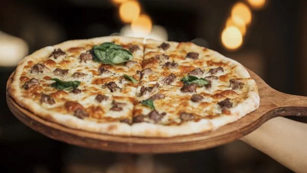 Pizza con diferentes ingredientes en una tabla de madera.