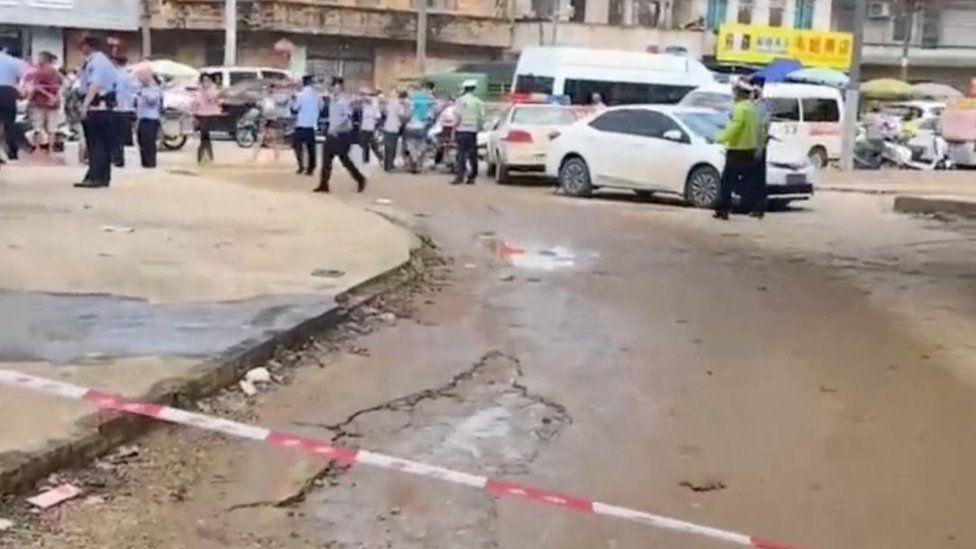 Personas y vehículos en una calle cerca de la guardería atacada.