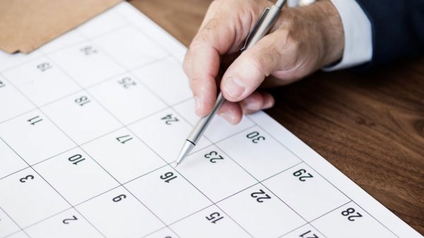 Mano revisando el calendario con un lápiz.