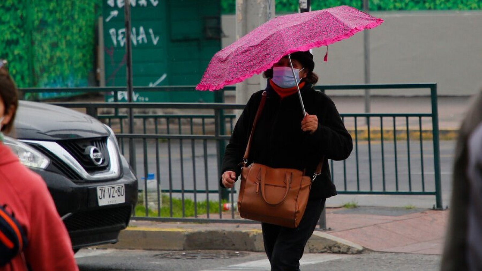 Mujer caminando bajo la lluvia con paraguas.