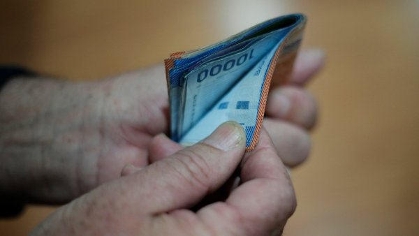 Mano sujetando billetes de diferentes montos.