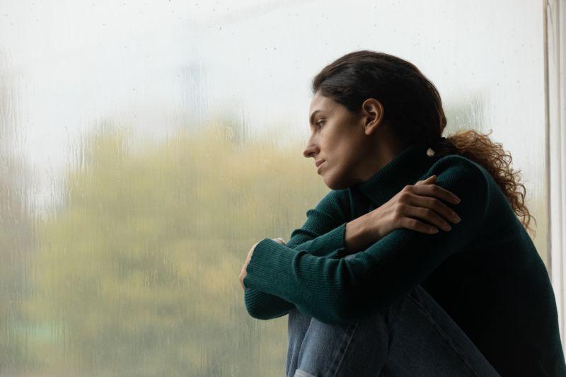 Una chica triste mirando por la ventana