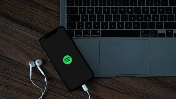 Teléfono con Spotify al lado de un computador.