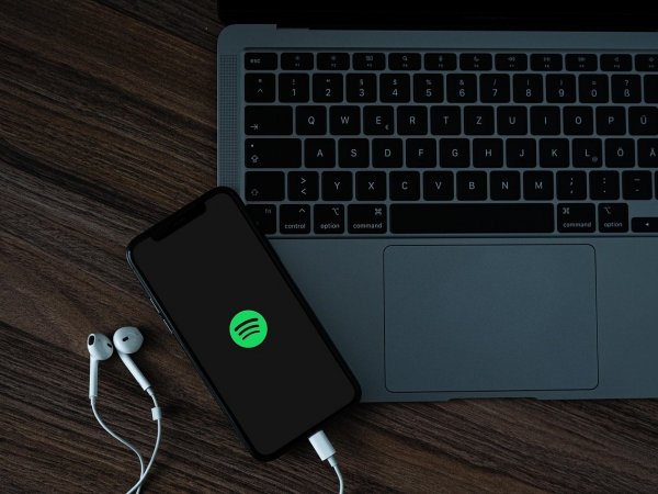 Teléfono con Spotify al lado de un computador.