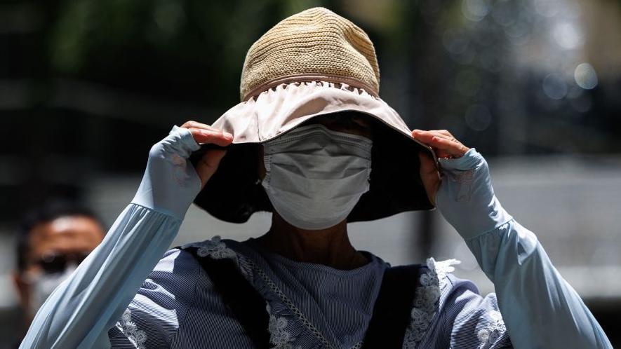 Mujer se tapa del sol en China con un sombrero.