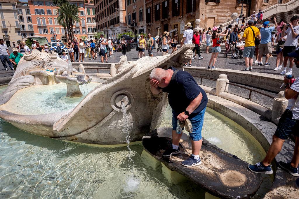 Un hombre se moja en una fuente de agua escapando del calor. 
