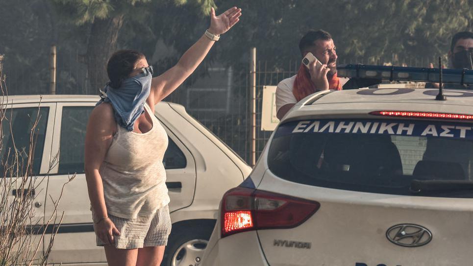 Una mujer se tapa la cara ante el humo en Grecia. 