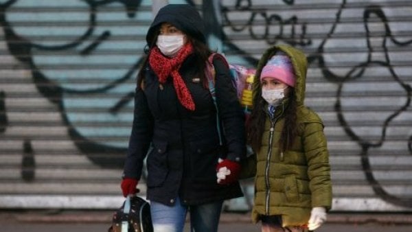 Mujer caminando con una niña en el frío.
