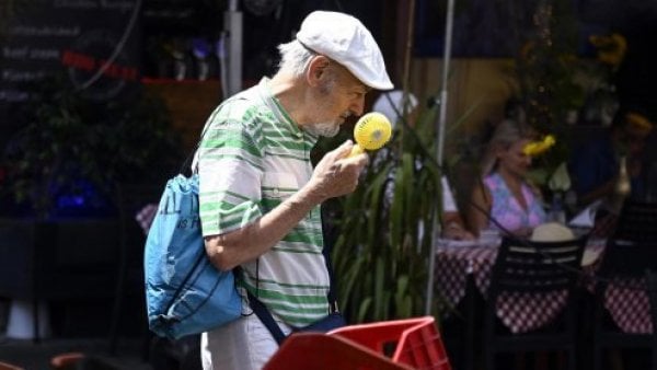 Persona mayor con un ventilador en la mano.