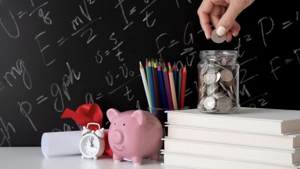 Objetos para representar educación financiera colocados en una mesa, como alcancía y monedas