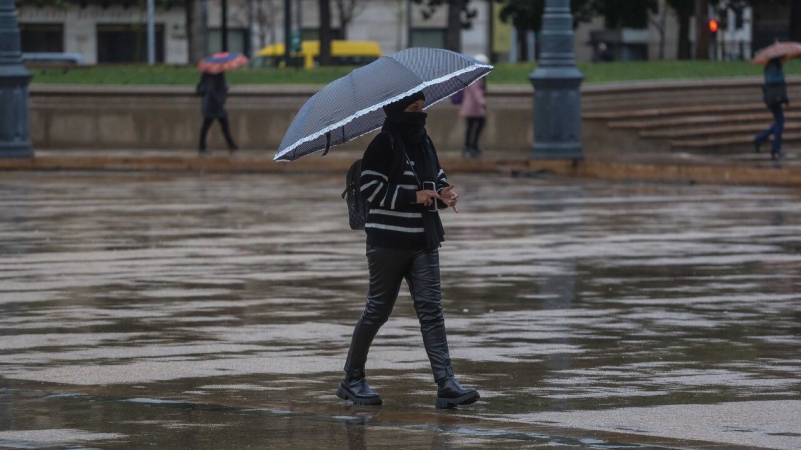 Mujer caminando bajo la lluvia con paraguas.