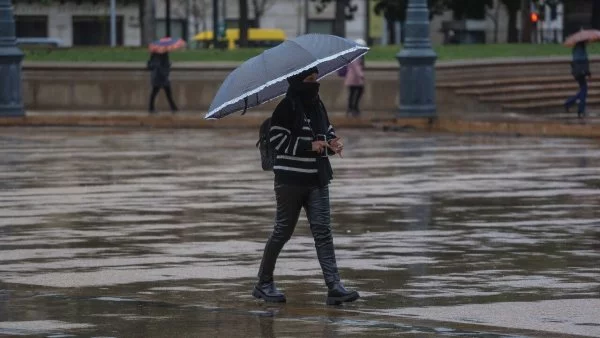 Mujer caminando bajo la lluvia con paraguas.