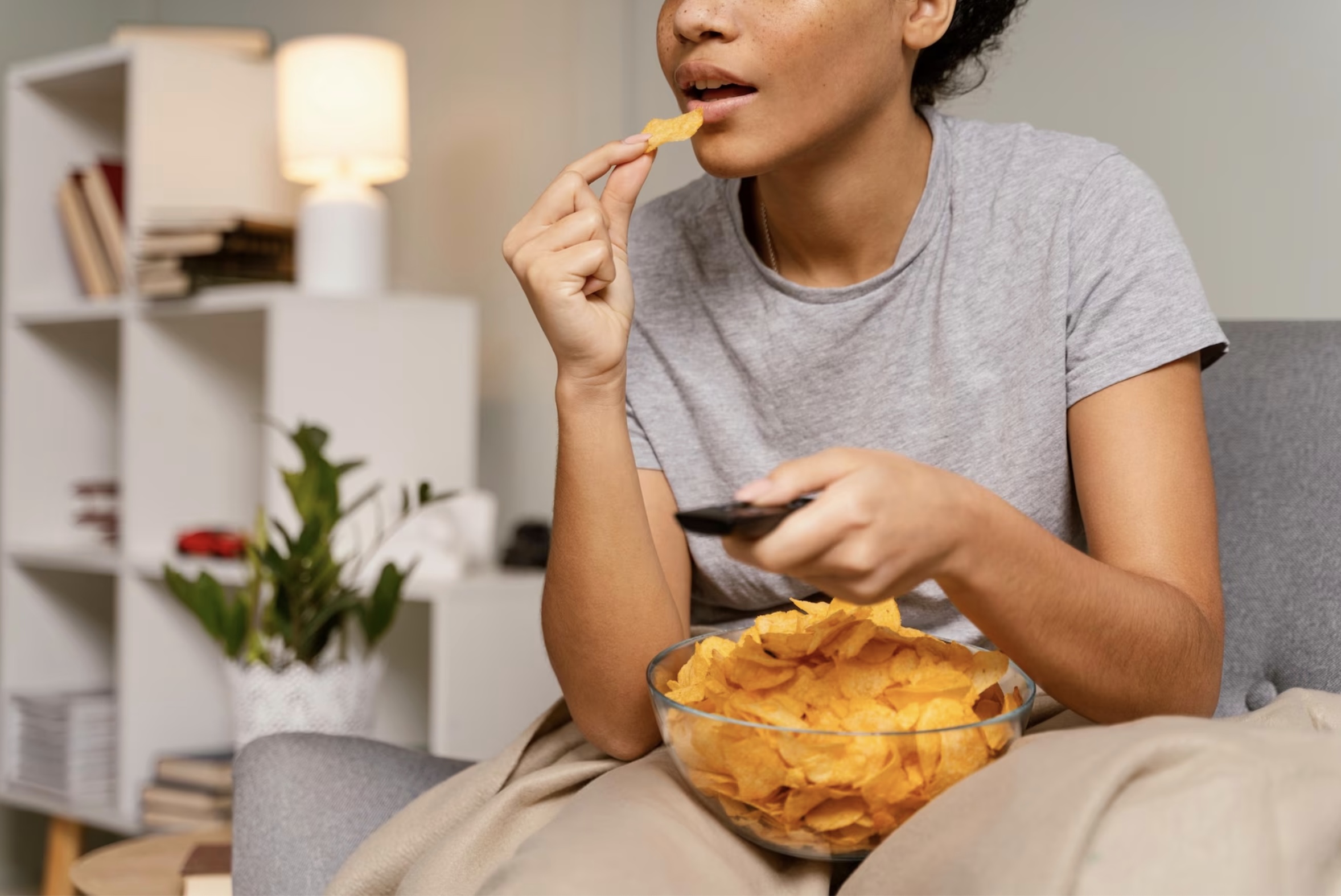 Mujer comiendo papas fritas en un sillón