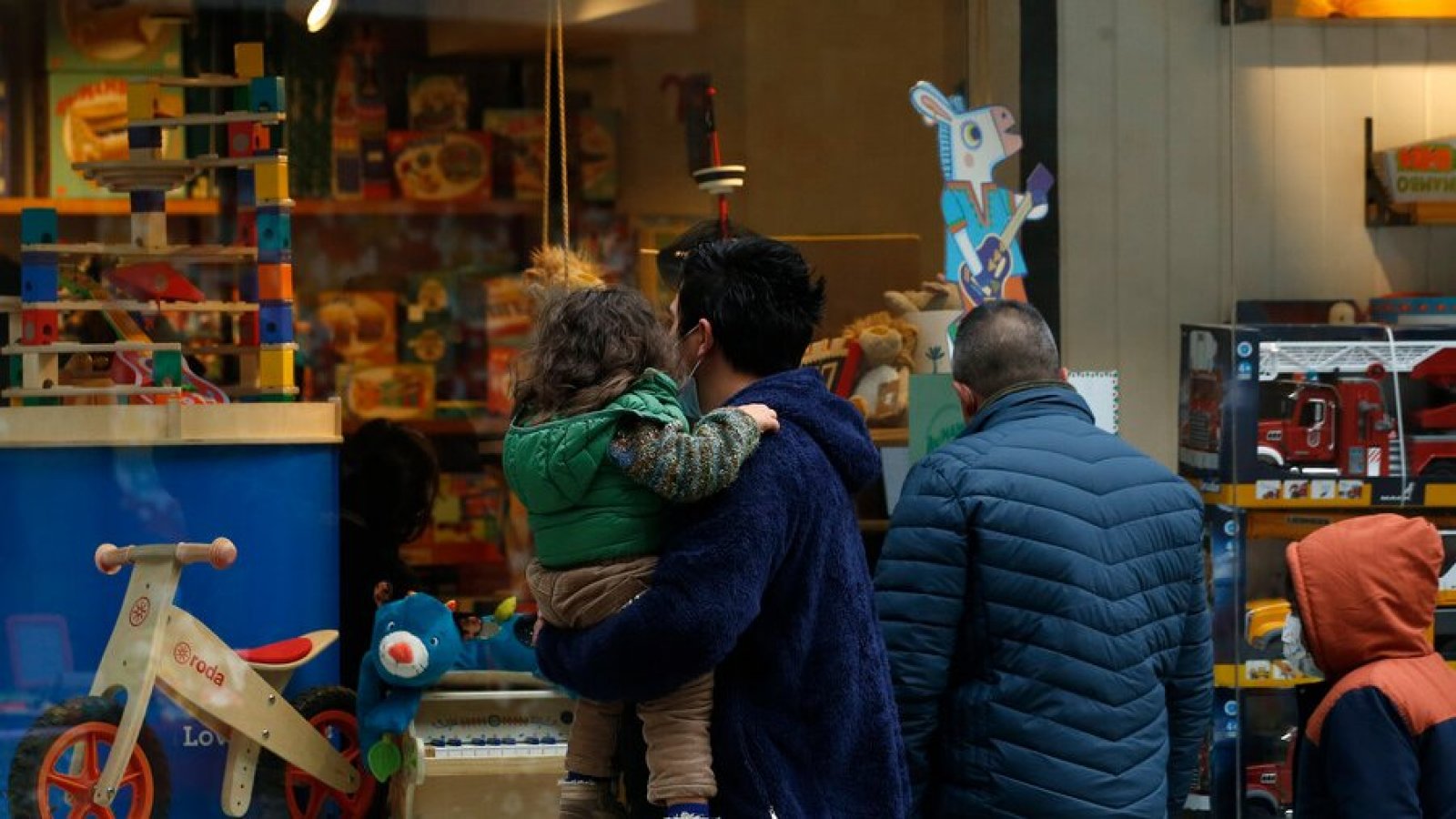 Padre con niña en brazos frente a una juguetería