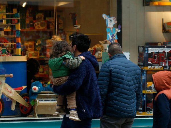 Padre con niña en brazos frente a una juguetería