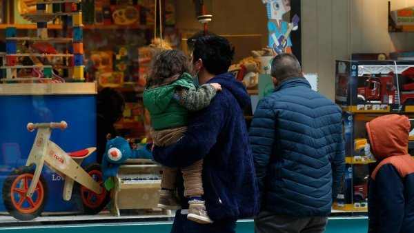 Padre con niña en brazos frente a una juguetería
