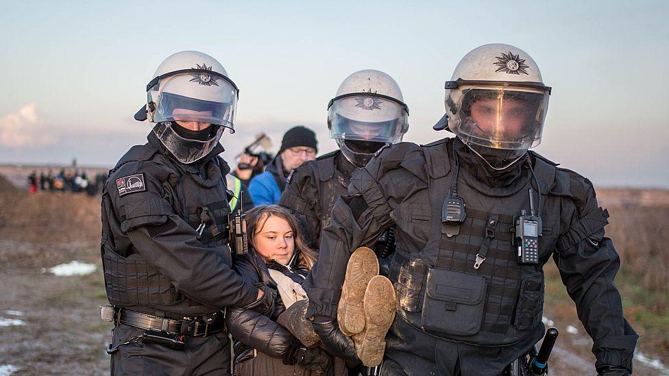 Thunberg cargada y retirada a la fuerta por tres policías 