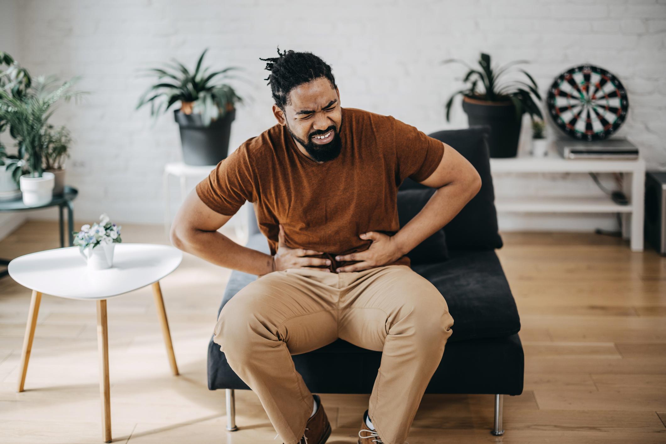 Hombre se toca el abdomen con dolor. 