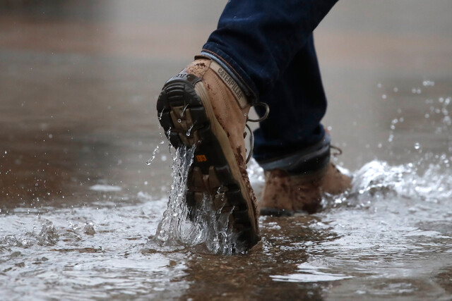 Persona caminando por zona bajo el agua. Lluvia en Santiago.