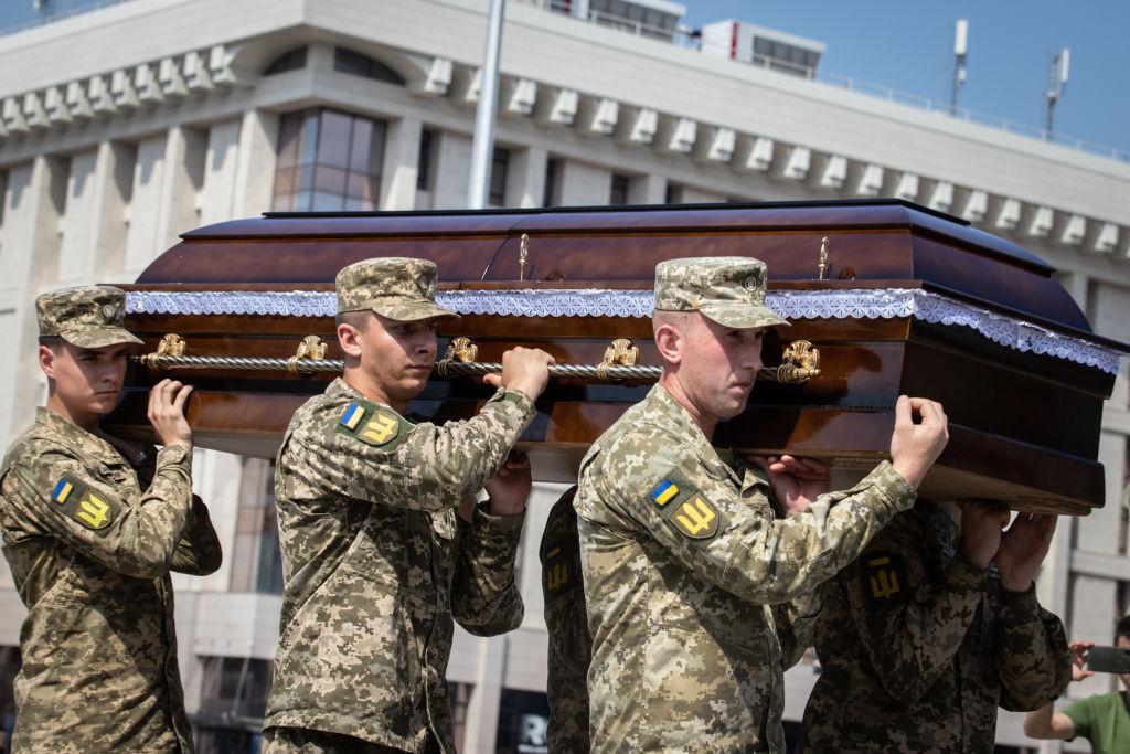 Unos soldados cargando el feretro de un compañero muerto.