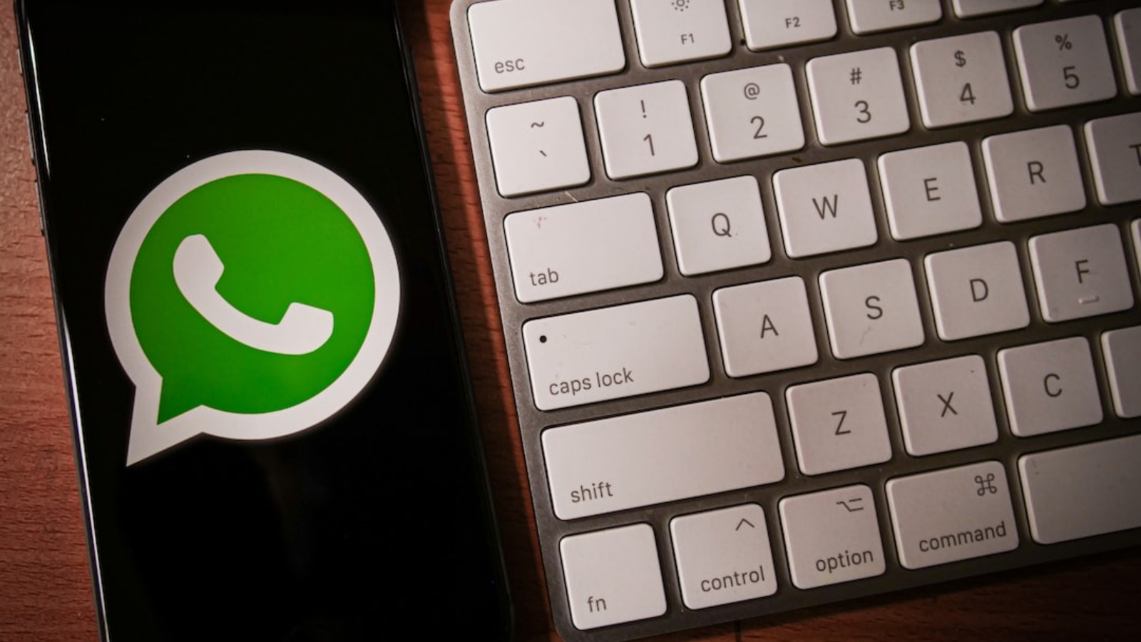 iPhone con logo de WhatsApp al lado de un teclado de computador