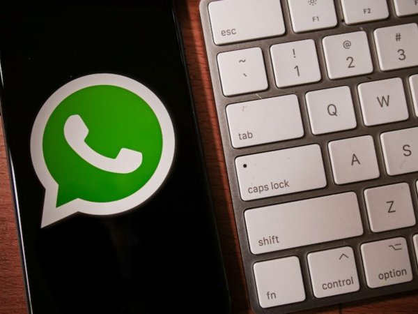 iPhone con logo de WhatsApp al lado de un teclado de computador