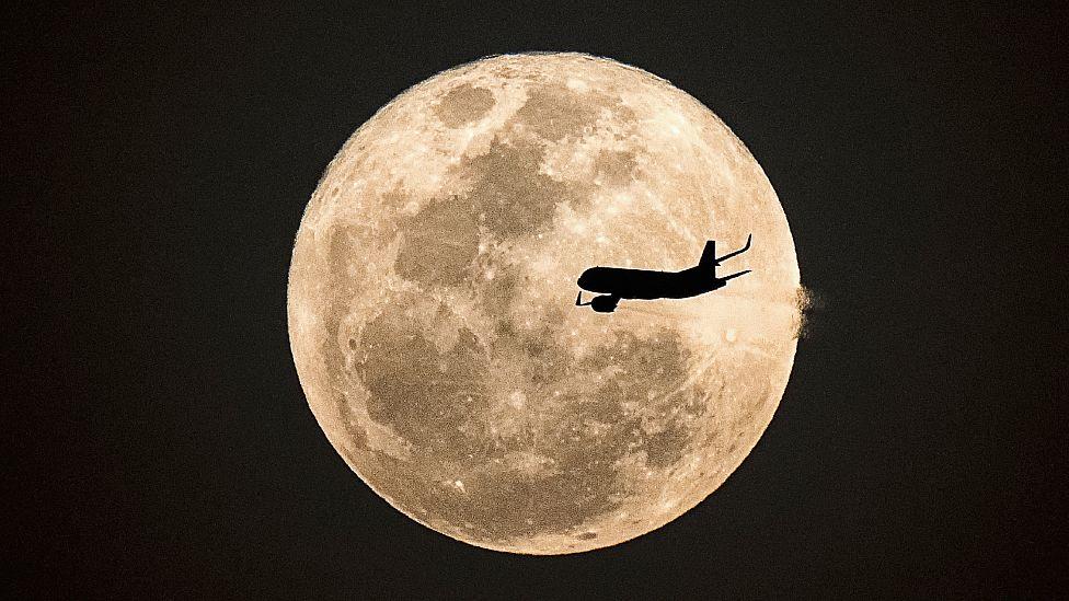 Un avión pasa delante de una súper Luna 