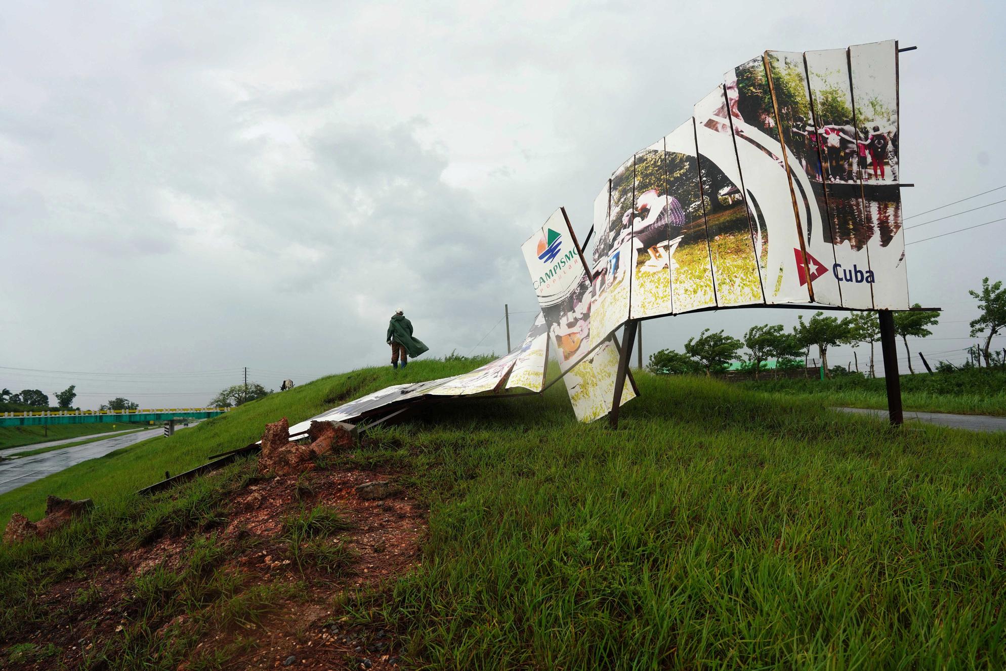 Roberto Arma, de 58 años, junto a un cartel publicitario destruido por la tormenta Idalia en Cuba.