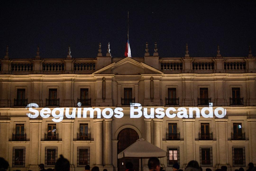 El palacio presidencial de La Moneda en Chile iluminado con la frase "Seguimos buscando", en referencia a los desaparecidos del régimen militar (1973-1990)