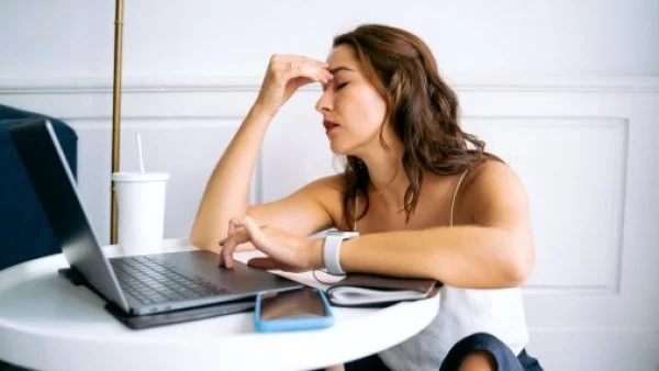 Cambio de hora. Mujer con dolor de cabeza en el trabajo.