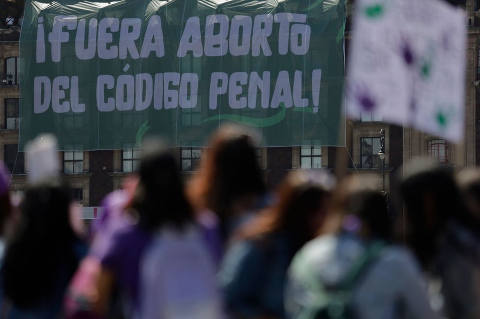 Una pancarta desplegada desde un edificio con el lema Aborto fuera del Código Penal, mientras grupos de mujeres se manifiestan frente al Palacio Nacional en la Ciudad de México, con motivo del Día Internacional de la Mujer, para exigir el fin de la violencia de género y la violencia machista, y justicia. para las víctimas de feminicidio y castigo para los perpetradores.