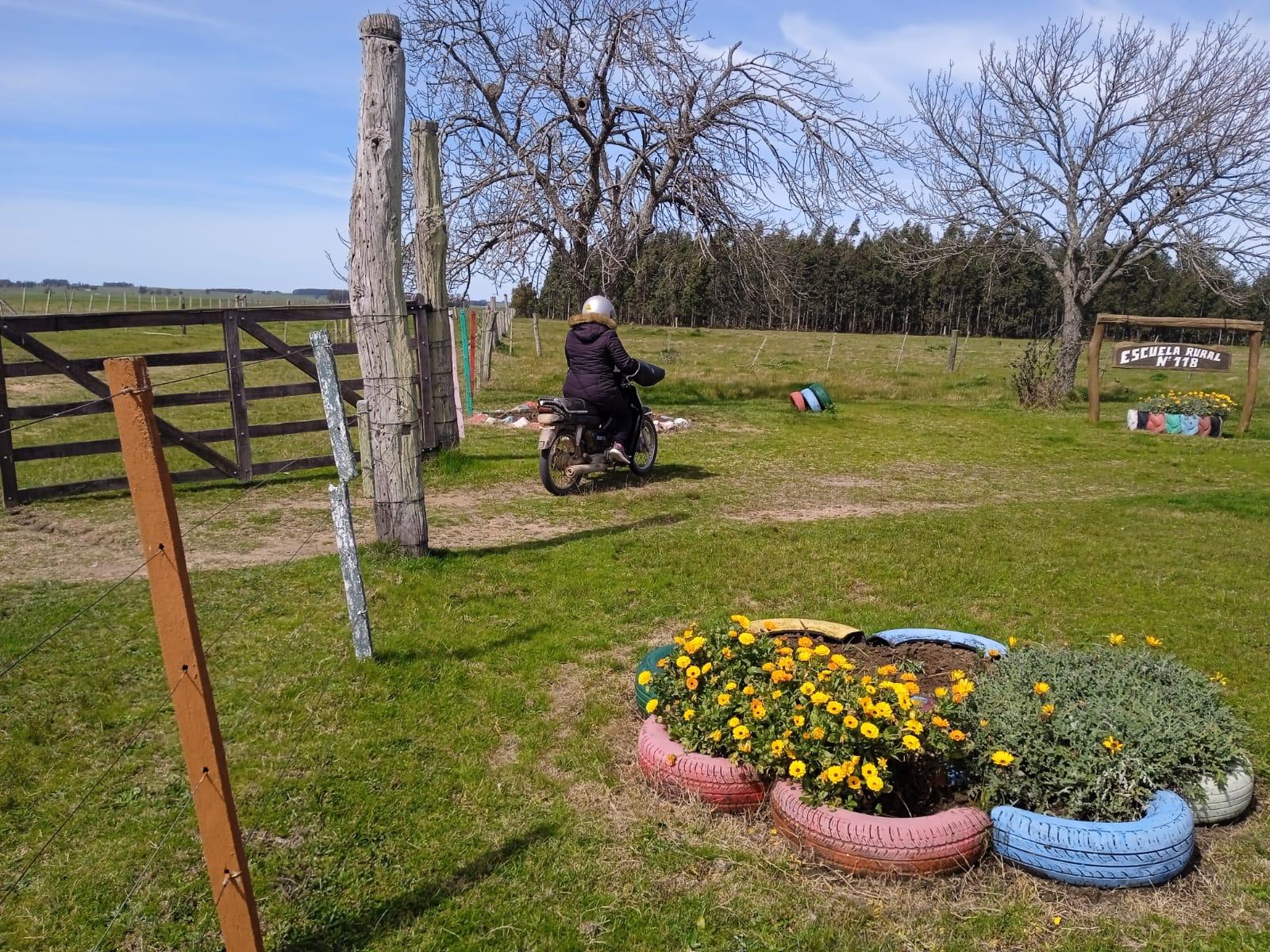 María Domínguez entra en el predio de la escuela rural 118 conduciendo una moto.