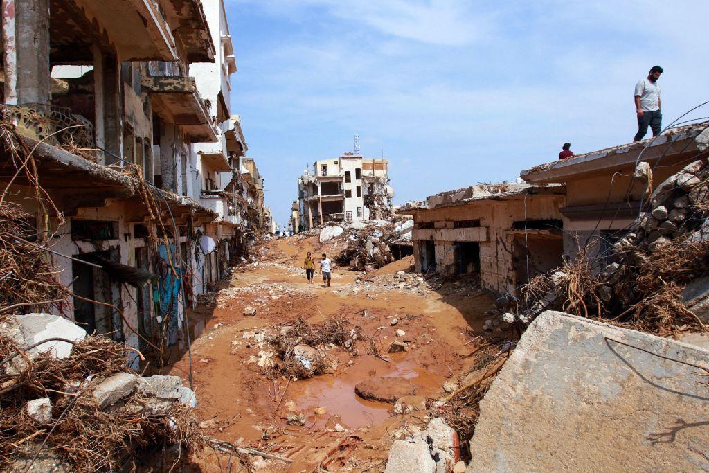 Dos personas caminan en medio de los escombros y destrozos que han dejado las inundaciones.