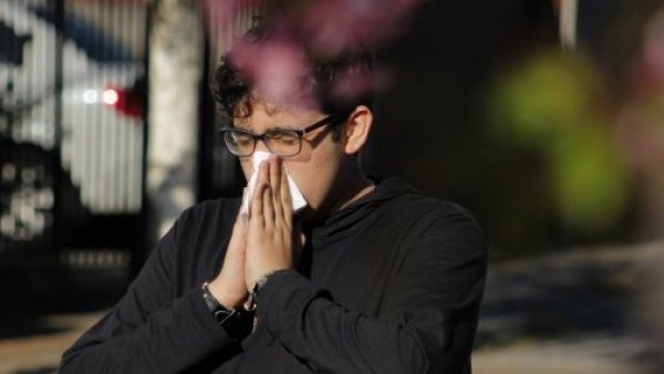 Hombre con pañuelo estornuda por resfrío o alergia