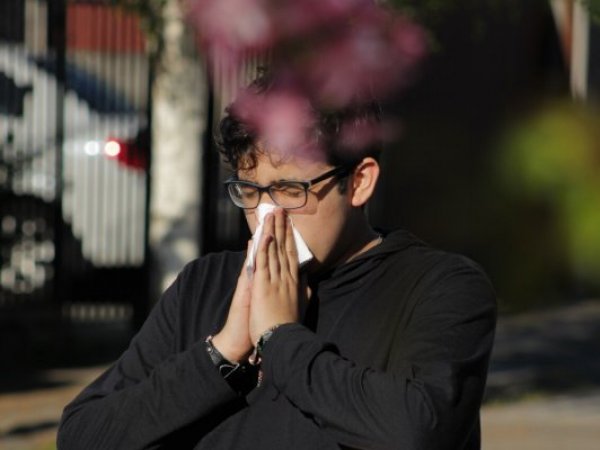 Hombre con pañuelo estornuda por resfrío o alergia