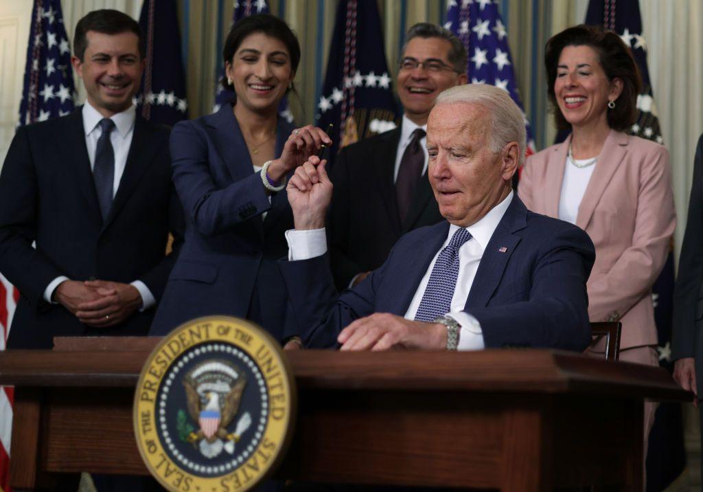 El Presidente de Estados Unidos, Joe Biden, pasa un bolígrafo para firmar a la presidenta de la Comisión Federal de Comercio, Lina Khan mientras el secretario de Transporte, Pete Buttigieg, el secretario de Salud y Servicios Humanos, Xavier Becerra, y la secretaria de Comercio, Gina Raimondo, observan durante un evento en la Casa Blanca el 9 de julio de 2021.