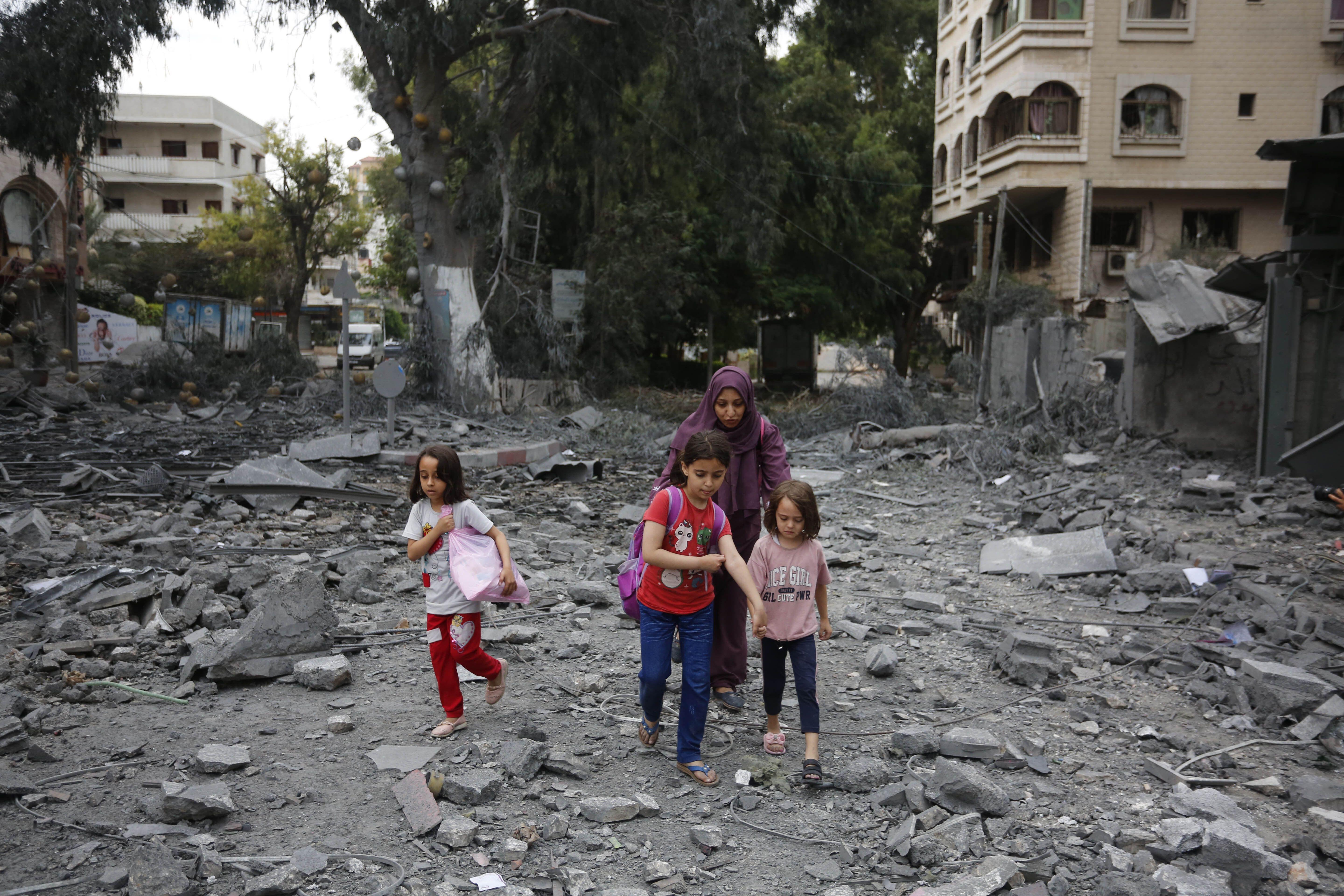 Mujeres y niños en Gaza caminando entre los escombros