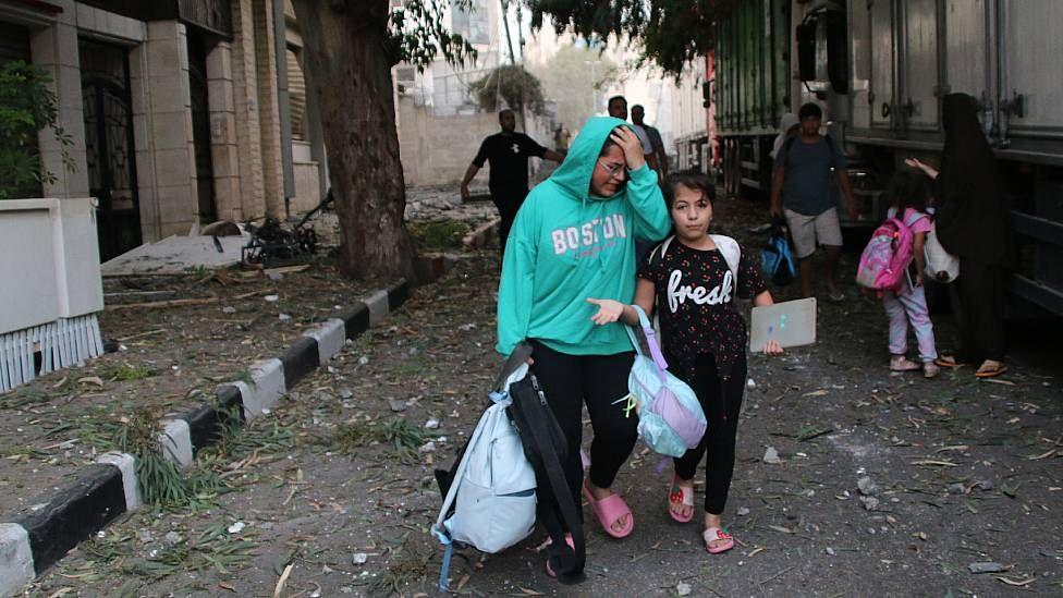 Mujer llorando y una niña con sus pertenencias en la calle