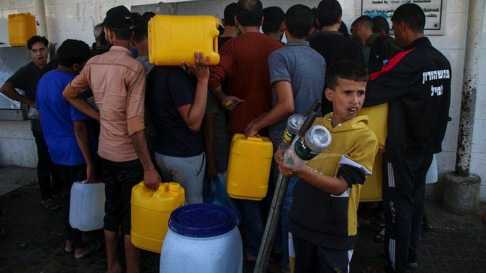 Palestinos llenan agua de estaciones de agua en la calle de Khan Younis, al sur de la ciudad de Gaza.