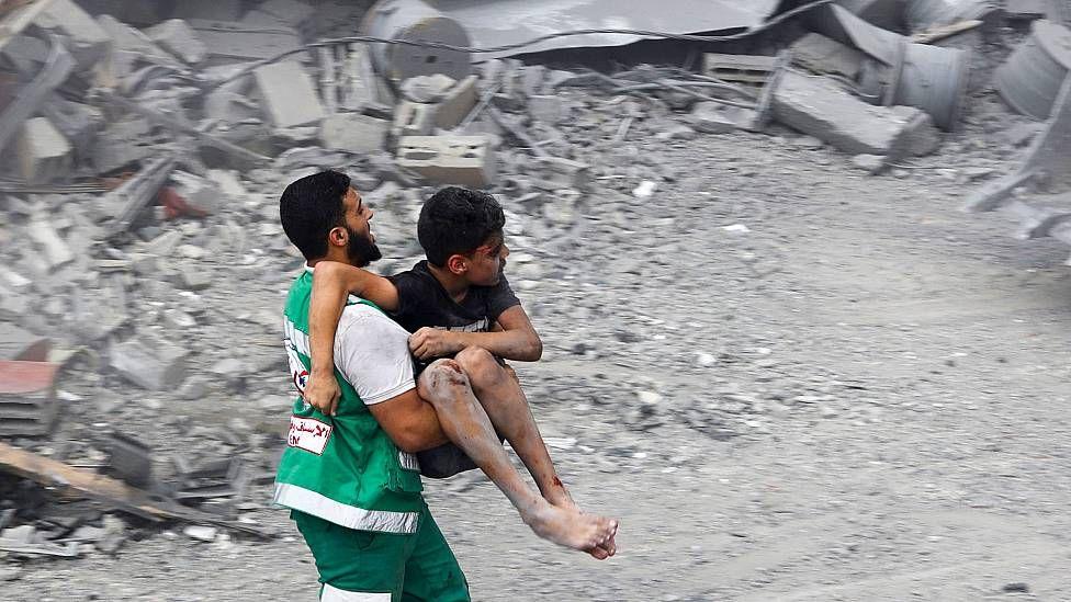 Un hombre corre llevando un niño herido a un hospital en Gaza