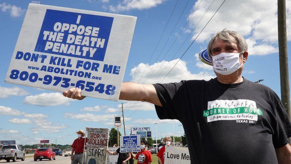 Una persona protesta con un cartel en contra de la pena de muerte