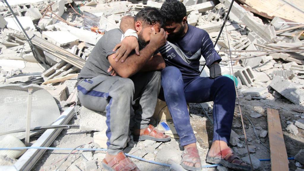 Dos palestinos lloran sobre los escombros de un edificio en el campo de refugiados de Shati en la ciudad de Gaza.