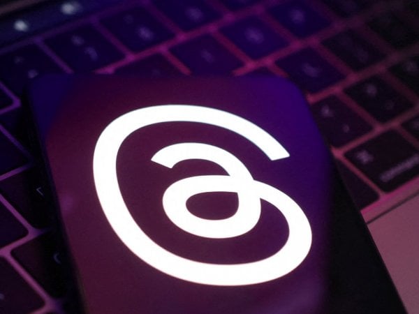 Logo de Threads en un celular sobre un computador. Threads web.