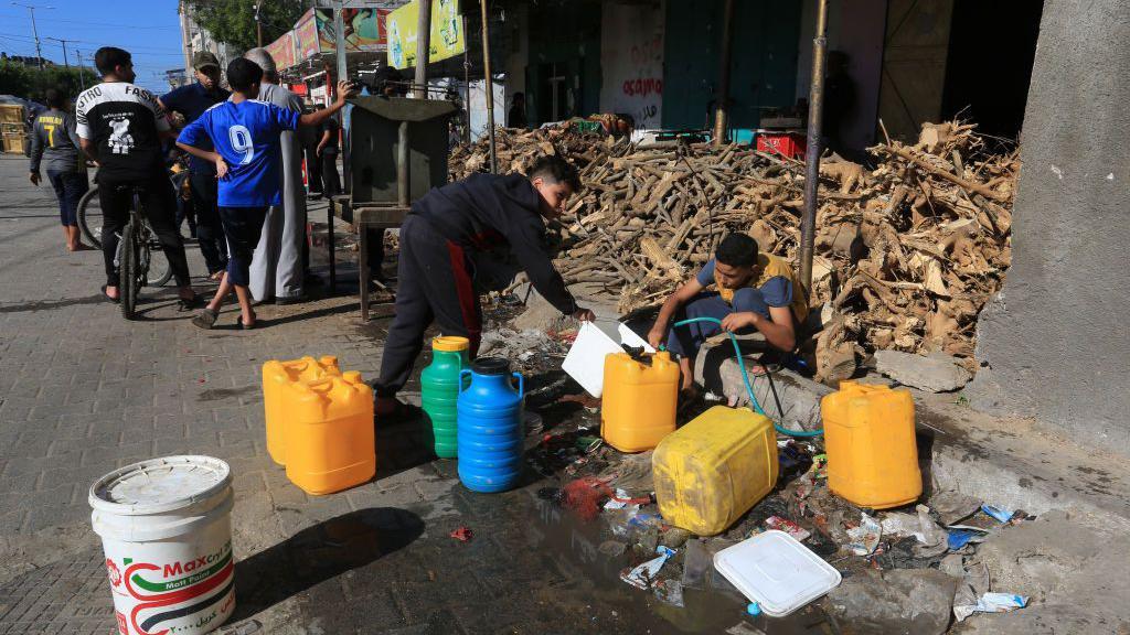 Un niño lleba botellas de agua cerca de Rafah