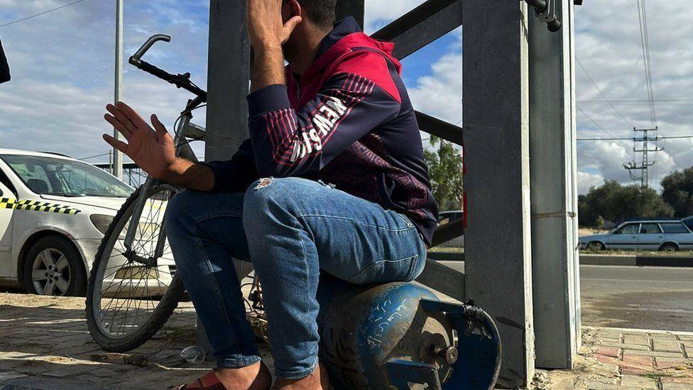 Un joven sentado sobre una bombona de gas para cocinar en Deir al-Balah.